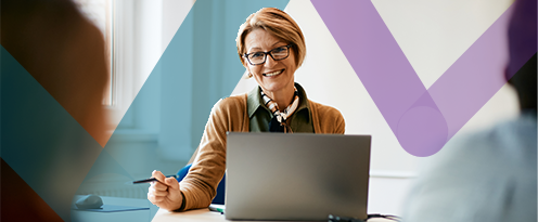 Teacher smiling in classroom on laptop