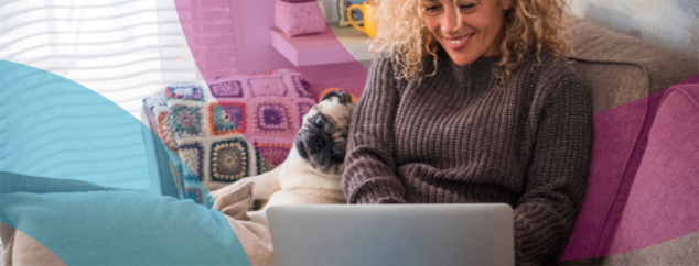 Woman sat indoors with her dog, looking at her laptop